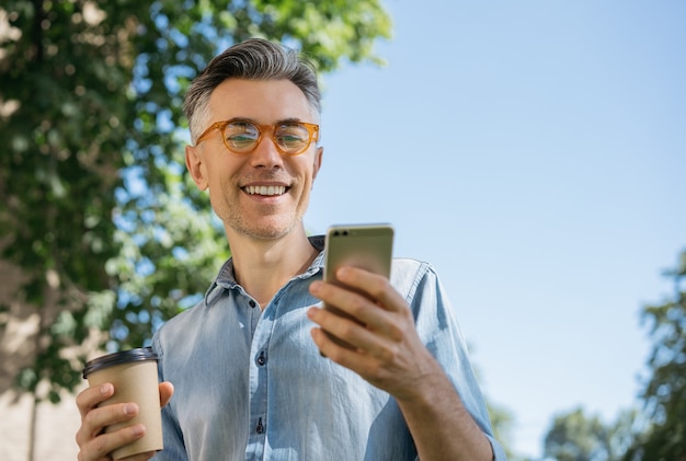 Stijlvolle volwassen man met behulp van mobiele telefoon