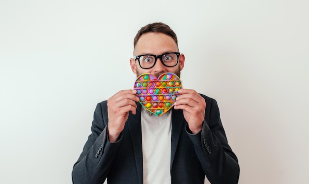 Foto stijlvolle vrolijke jonge hipster man met baard speelt met een populair speelgoed pop it anti stress zintuiglijke fidget push pop speelgoed