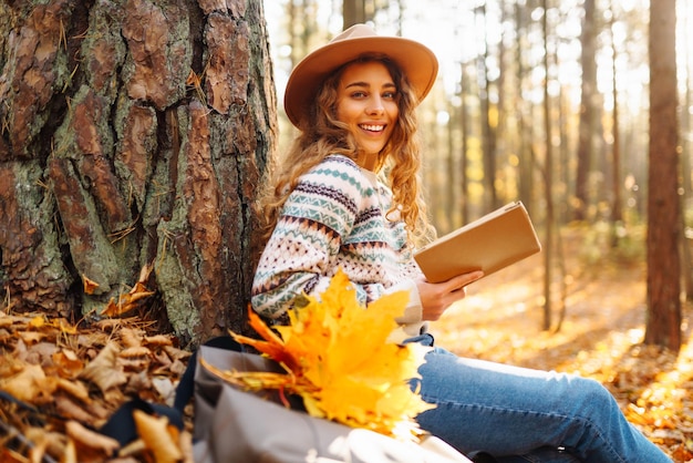 Stijlvolle vrouw die een boek leest in het herfstpark ontspanning genieten van eenzaamheid met de natuur