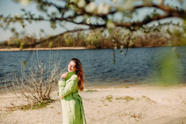 Stijlvolle vrouw groene jas achtergrond voorjaar bloeien