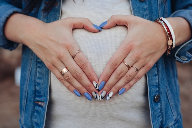 Stijlvolle vrouw in jeans jasje bedrijf palmen op buik