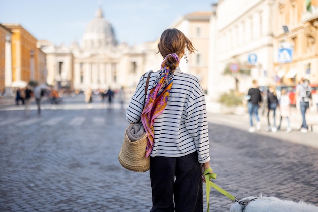 Stijlvolle vrouw loopt met een hond op straat in Rome