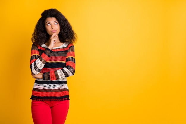 Stijlvolle vrouw met afrokapsel poseren tegen de oranje muur