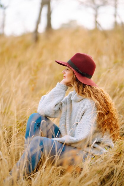 Stijlvolle vrouw met hoed die geniet van herfstweer in het park Modestijlconcept