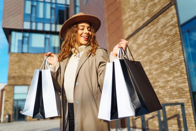 Stijlvolle vrouw met winkelzakken loopt door de straten van de stad Consumentisme winkelen levensstijl concept