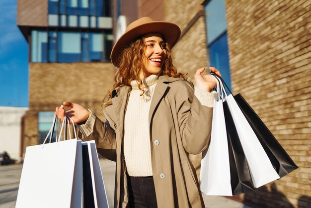 Stijlvolle vrouw met winkelzakken loopt door de straten van de stad Consumentisme winkelen levensstijl concept