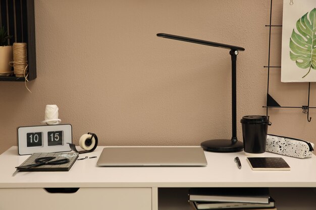Stijlvolle werkplek met laptop op wit bureau in de buurt van beige muur Interieurontwerp