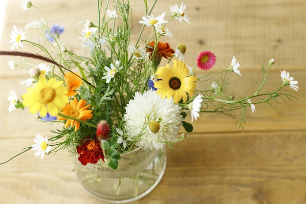 Stijlvolle wilde bloemen boeket in zonlicht op rustieke houten tafel Mooie zomerbloemen in vaas verzameld uit tuin bloemstuk in huis op het platteland