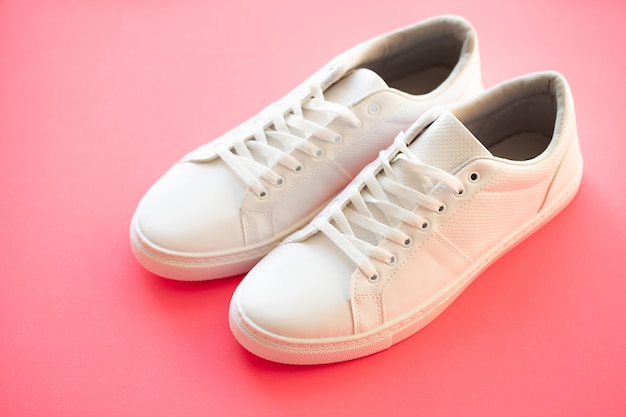 Stijlvolle witte mode sneakers op roze.