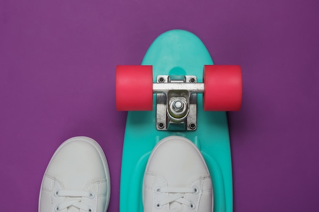 Stijlvolle witte sneakers met cruiserboard op paars papier