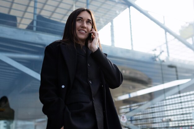 Stijlvolle zakenvrouw baas praten aan de telefoon op de achtergrond van de glazen gevel van de