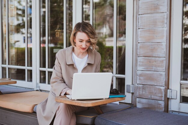 Stijlvolle zakenvrouw in een straatcafé die op laptop werkt