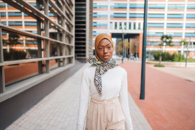 Stijlvolle zwarte vrouw met hoofddoek die op straat staat