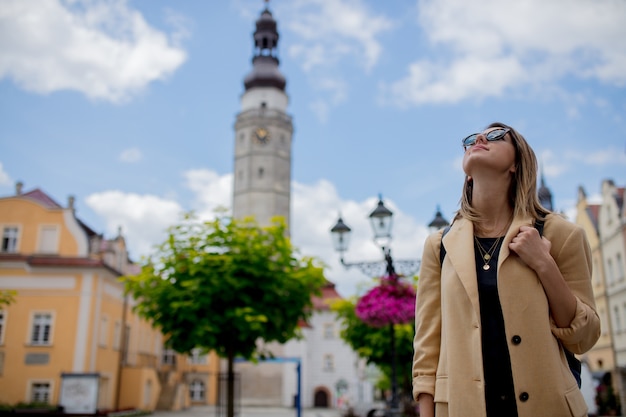 Stijlvrouw in zonnebril en rugzak op het oude plein van het stadscentrum. Polen
