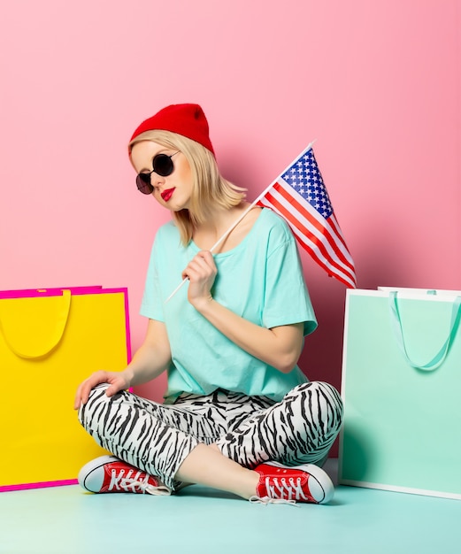 Stijlvrouw in zonnebril met het winkelen zakken en de vlag van de VS