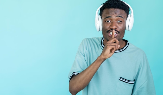 Stil gebaar Geheime man Beste geluid Hipster man in witte koptelefoon met vinger op lippen geïsoleerde blauwe kopie ruimte