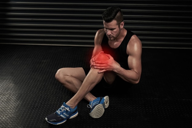 Photo still feeling some pain on his knee high angle shot of an athletic young man working out with an injury in the studio