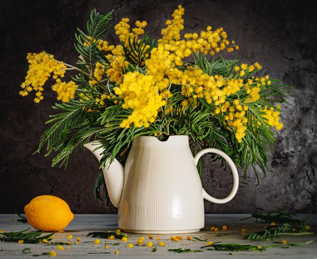 Still life  acacia white teapot and lemon on a gray background