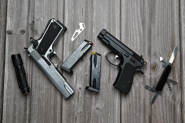 Photo still life of black and silver handgun with cartridge magazine flashlight knife multipurpose tool