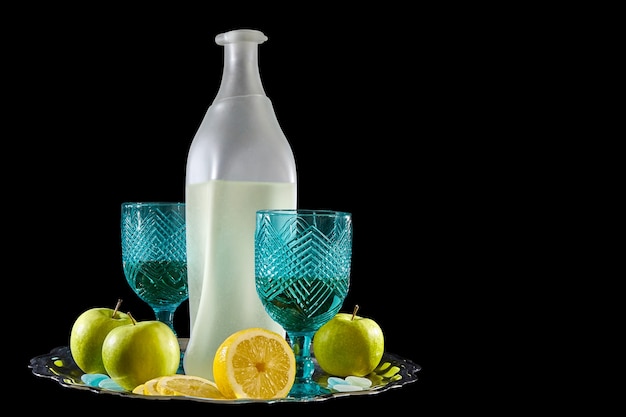 Natura morta di una bottiglia di limonata, bicchieri e limoni su sfondo nero