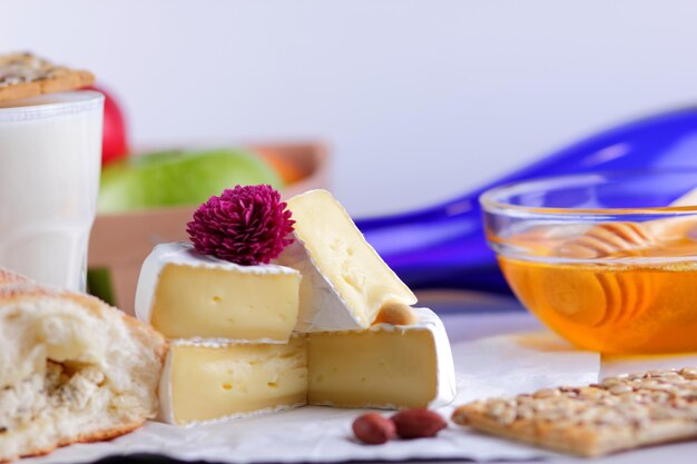 Still life of cheese honey walnuts fruit and a blue bottle on a blurred background Food for a healthy and tasty snack on a white parchment Closeup