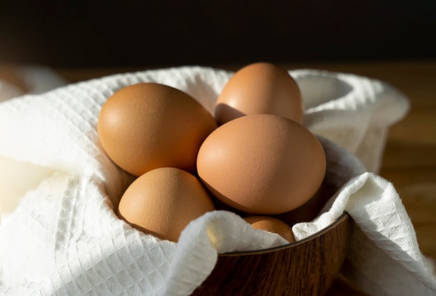 Натюрморт из куриных яиц в миску на деревянный стол на кухне. Ассортимент яиц, натуральные сельскохозяйственные продукты. Здоровая пища во время