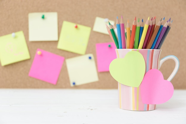 Still life color pencils in colorful cup on wooden table and post it note for insert your text