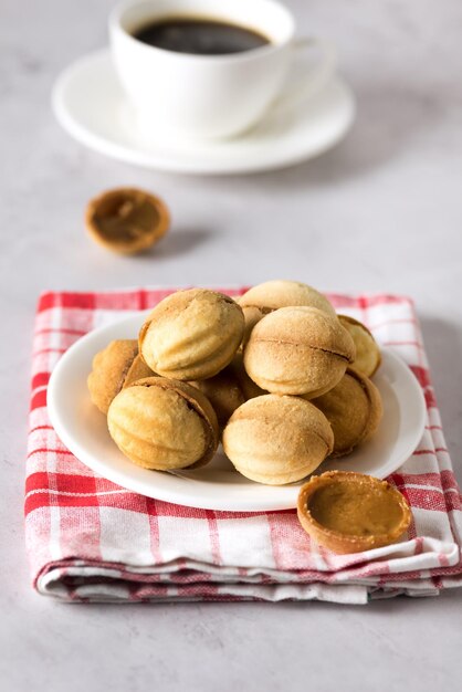 Still life Composition with White Plate Cup of Coffee Walnuts Sweet Cookies Shaped