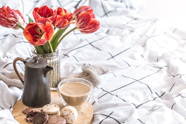 Still life accogliente colazione con caffè e dolci amaretti. con bellissimi tulipani rossi in camera da letto