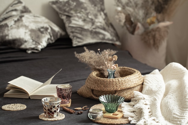 Photo still life cozy house with decorative details in the interior . household items and comfort. candles and a book lie on the bed in the living room.