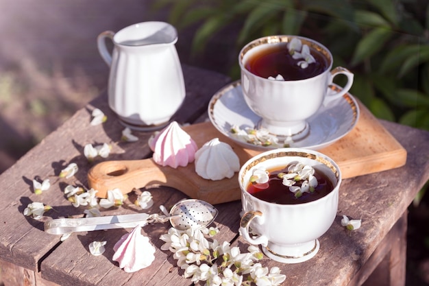 Still life cups of tea meringues and flowers