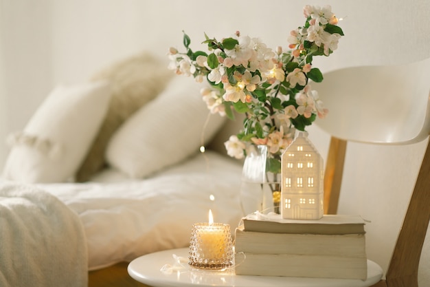 Still life details in home interior of living room. Book, candle and vase with apple spring flowers. Read and rest