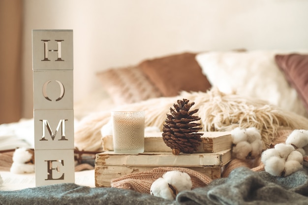 Still life details in home interior of living room and the inscription HOME. Books and cup of tea with cone and cotton. Read, Rest. Cozy autumn or winter concept, knitwear. Cozy autumn winter concept