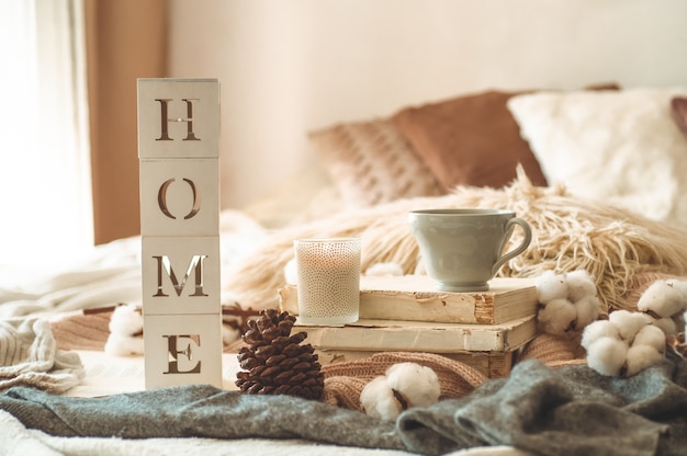 Still life details in home interior of living room and the inscription HOME. Books and cup of tea with cone and cotton. Read, Rest. Cozy autumn or winter concept, knitwear. Cozy autumn winter concept