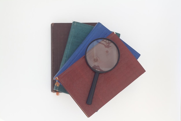 Still life from a magnifier and a pile of old books on a white background