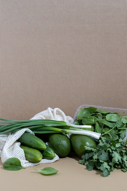 Still life of green vegetables in eco bags on a beige background Healthy vegetarian food