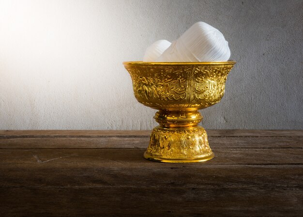 still life of holy thread in Thailand Gold tray with pedestal on wooden table with grunge background