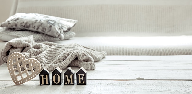 Still life in hygge style with wooden word home, heart and knitted element. concept of home comfort and modern style.