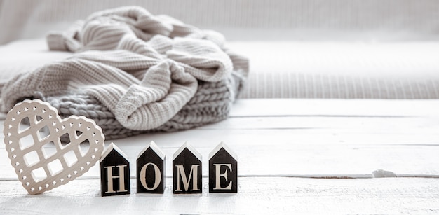 Still life in hygge style with wooden word home and knitted element. concept of home comfort and modern style.