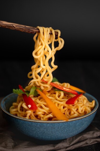 Still life instant noodles with sliced bell pepper on chopstick.