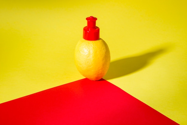 Foto natura morta minimalista di un sapone liquido al limone su sfondo rosso e giallo