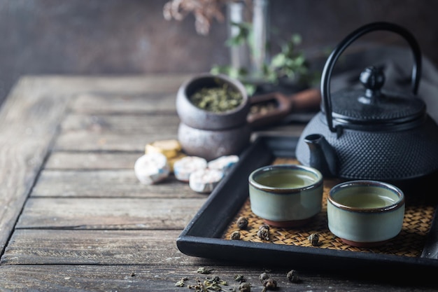 写真 暗い背景の上の小さなカップとティーポットで日本の健康的な緑茶の静物