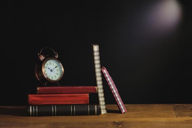 Still life old text book and alarm clock on table.