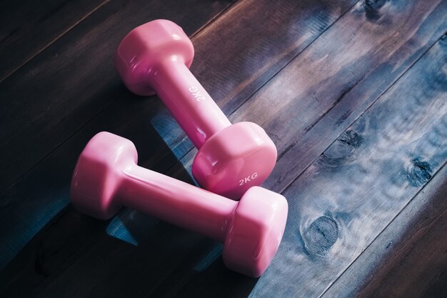 Still life overhead shot of two pink dumbbells on wooden floor