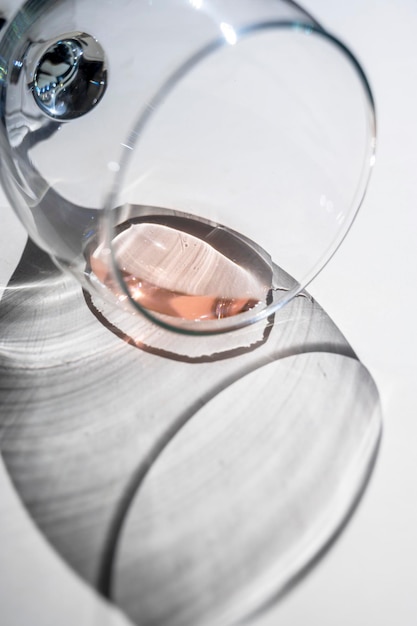 厳しい影と日光の下でベージュ色の背景にワイングラスのある静物シーン 抽象的な飲むワインのコンセプト