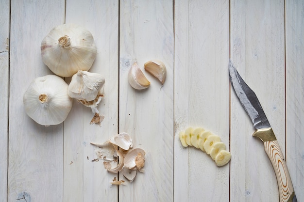 Still life of some heads, some cloves and slices of garlic on a white wooden table