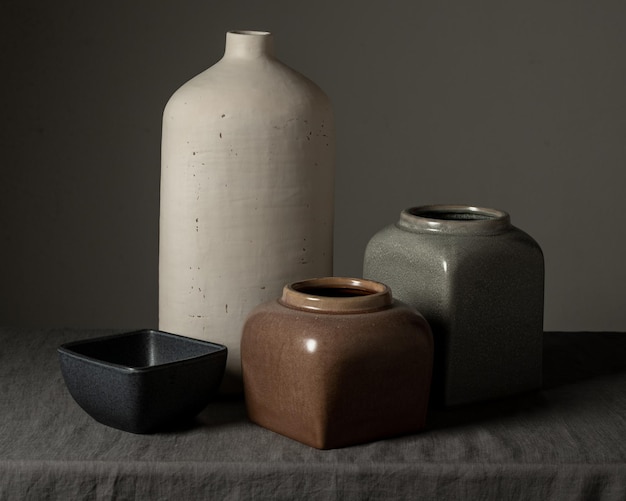 Still life square black matte clay plates and cup and milk jug and vases of various shapes