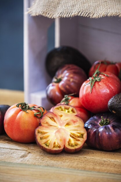 Still life of tomatoes of various types with some chopped a pink wooden box on a wooden board