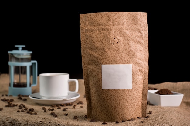 still life of unbranded coffee packaging in different colors and natural backgrounds next to cups coffee pot and coffee