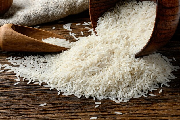 Still-life of Uncooked long rice spilled out from the bowl on old wooden table.